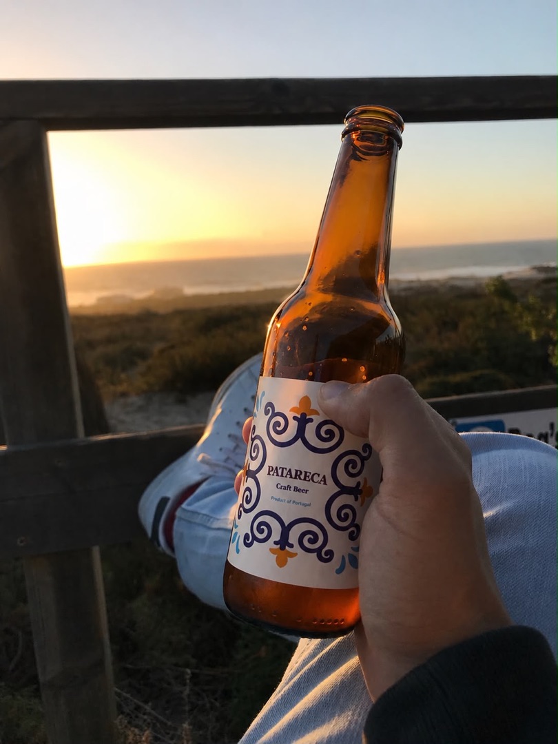 A bottle of Patareca held against an ocean sunset